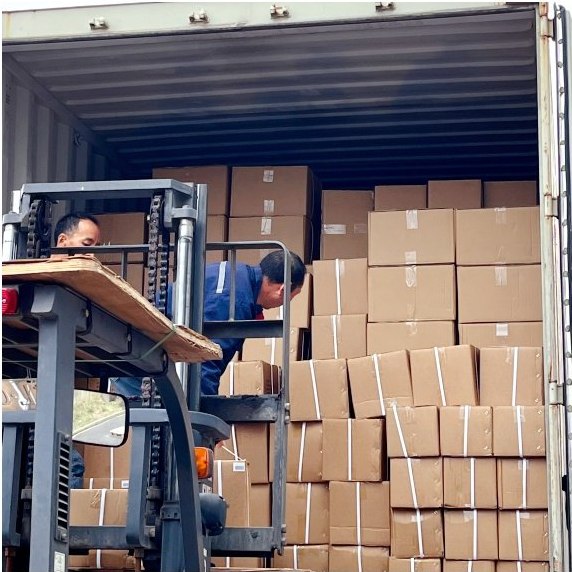 Forklift feeding cartons into a container already stacked floor-to-ceiling